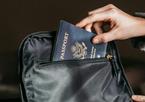 Close-up of a person placing a passport into a leather bag, ready for travel.